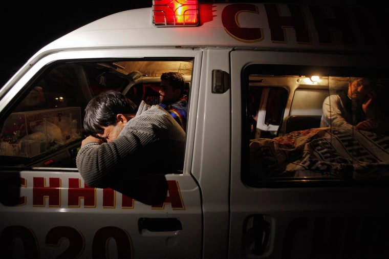 Image: A relative mourns his family member, who was killed by unknown gunmen, next to his body in an ambulance, in Karachi.