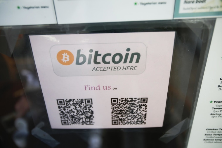 A bitcoin logo is seen at the window of a restaurant that accepts bitcoin.