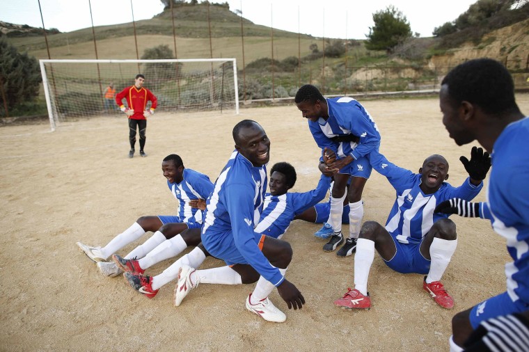 Image: African migrants, who are members of the ASD Mineo soccer team, celebrate after scoring against Massiminiana in the Sicilian village of Mineo