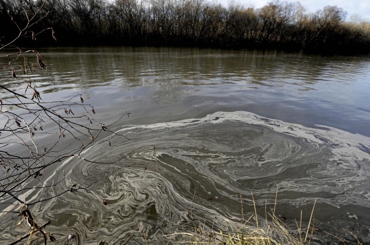 In this Wednesday, Feb. 5, 2014 photo, signs of coal ash swirl in the water in the Dan River in Danville, Va. Duke Energy estimates that up to 82,000 tons of coal ash has been released from a break in a 48-inch storm water pipe at the Dan River Power Plant in Eden N.C.