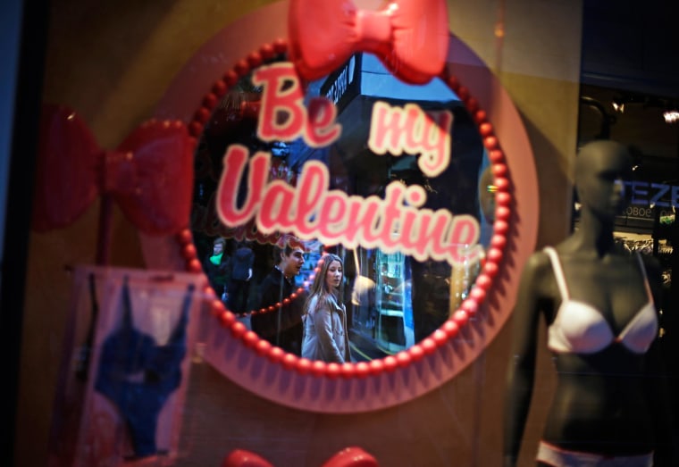 A couple walk past a lingerie shop advertising the upcoming Valentine's Day holiday in the Sochi city center, Monday, Feb. 10, 2014, in Sochi, Russia, home of the 2014 Winter Olympics. (AP Photo/David Goldman)