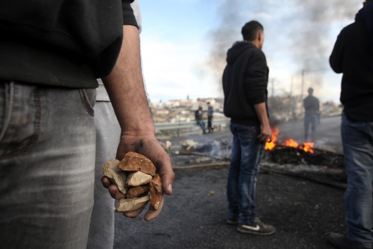 Image: A Palestinian protester holds stones during clashes with Israeli soldiers