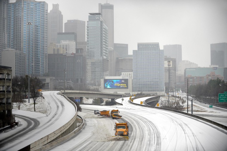 Image: Snow plows clear Interstate 75/85 on the downtown connector while transportation and business grinds to a halt during a winter storm on Wednesday in Atlanta.