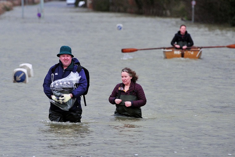 Image: A couple wade along a flooded road Wednesday near Egham, west of London.