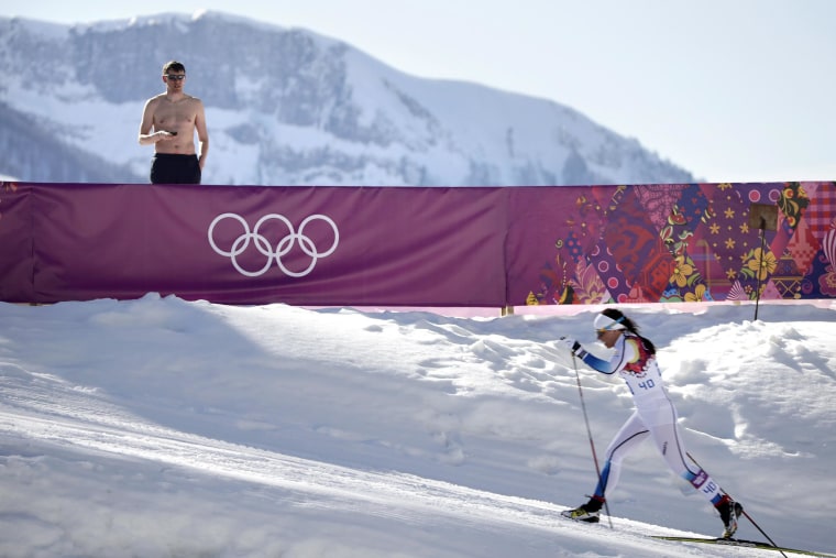 A shirtless spectator watches Sweden's Charlotte Kalla compete during the women's 10K classical style cross-country race at the 2014 Winter Olympics on Feb. 13 in Krasnaya Polyana, Russia. Kalla won the silver medal.