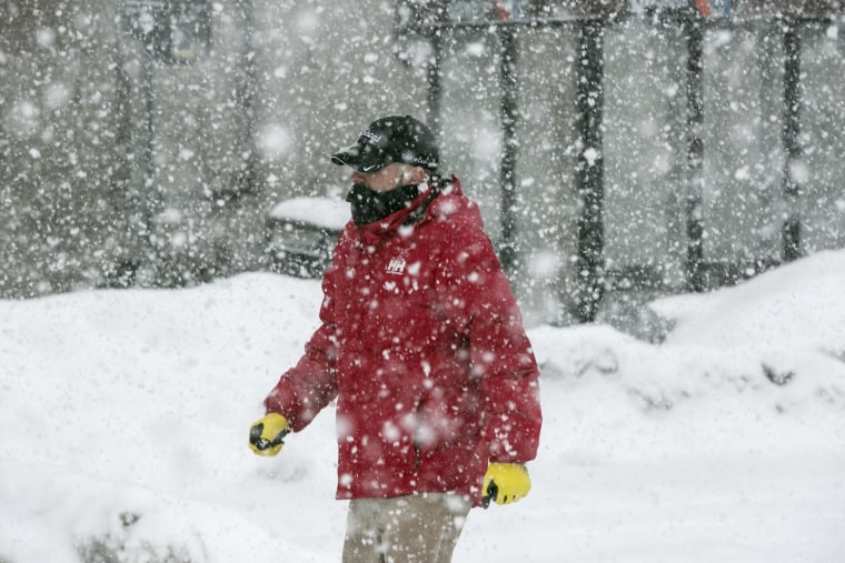 Image: Snow falls as commuters begin their day.