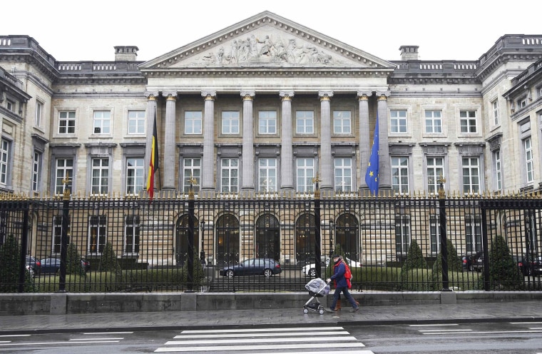 Image: A couple pushes a baby in a trolley in front of the Belgian Parliament in Brussels