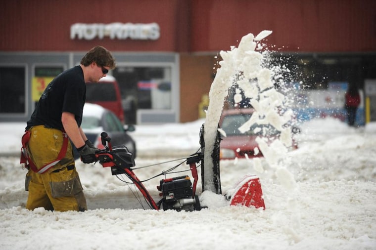 Image: Matthew Cunningham uses a snow blower to clear the sidewalk.