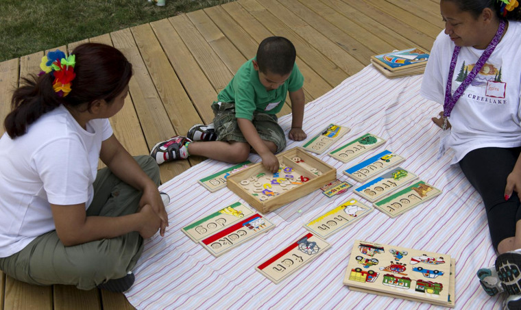 Lorena Arcos (left) and Jessica Castro (right), mothers trained by Chicago's Logan Square Neighborhood Association to advocate for early learning in their community, work with a boy from the neighborhood on his letters during an educational playgroup they helped organize.