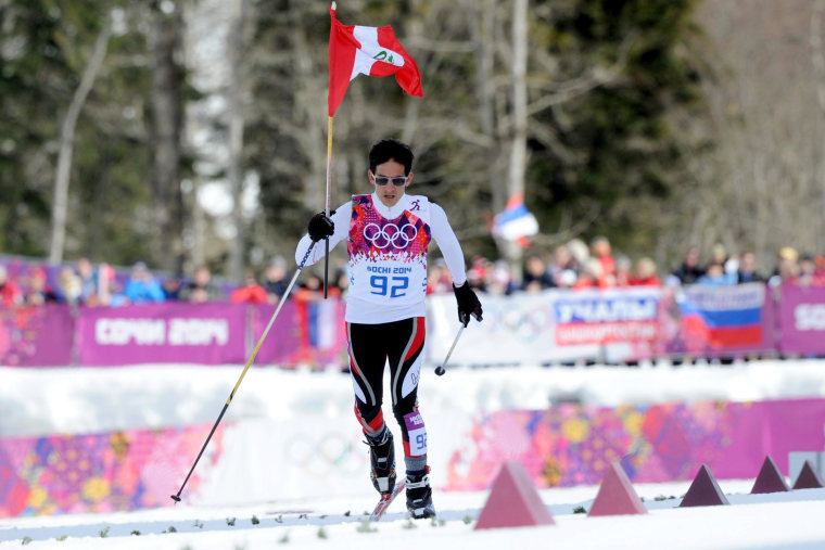 Peru's Roberto Carcelen holds up his national flag as he finishes last in the Men's Cross-Country Skiing 15km Classic during the Sochi Winter Olympics on February 14, 2014 in Rosa Khutor near Sochi.
