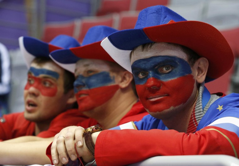 Image: Fans with their faces painted in the colours of the Russian flag look on before the men's preliminary round ice hockey game between Russia and USA at the Sochi 2014 Winter Olympic Games