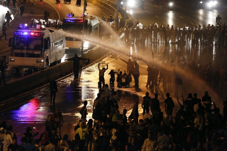 Image: Riot police use water to disperse opposition demonstrators as they block the city's main highway in Caracas