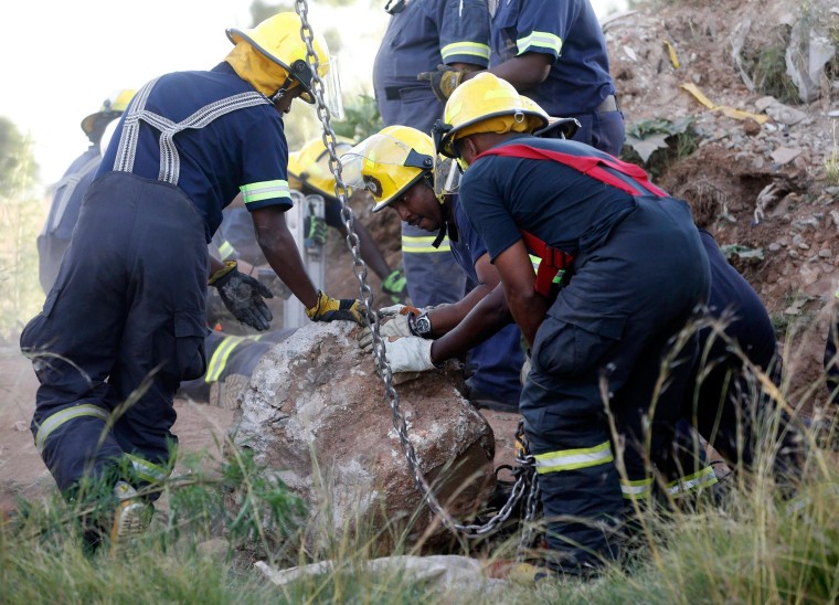Image: Rescue officials move a rock removed from an abandoned gold shaft as they work to rescue trapped suspected illegal miners in Benoni