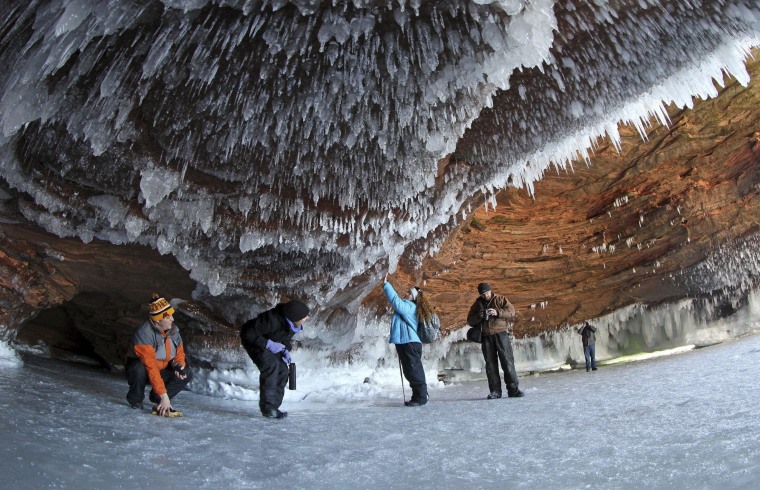 Image: Sightseers crouch to avoid icicles in a sea cave on frozen Lake Superior at the Apostle Islands National Lakeshore