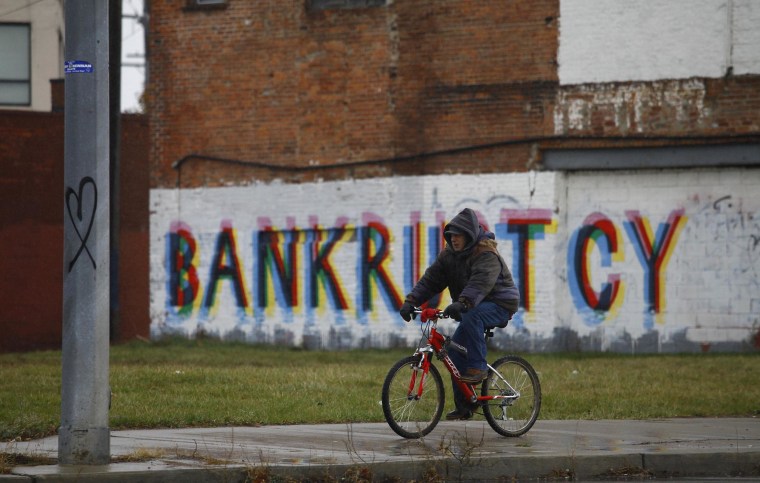 Image: A man rides his bike past graffiti in Detroit