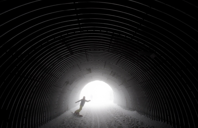 A snowboarder goes through a tunnel near the alpine skiing training slopes at the Sochi 2014 Winter Olympics on Feb. 17 in Krasnaya Polyana, Russia.
