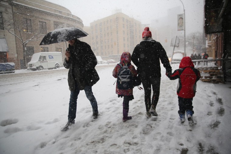 Image: A person walks two kids to school during a snowstorm