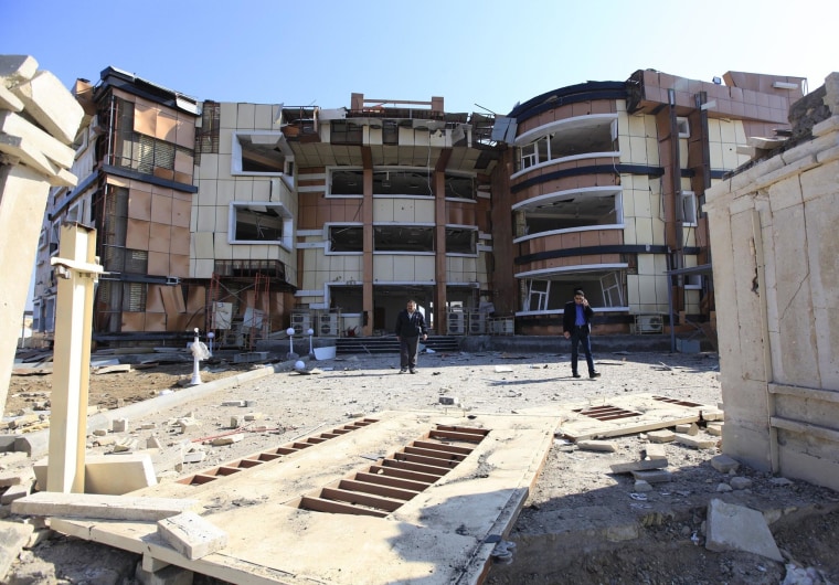 Image: People gather at the site of a bomb attack at a damaged building of the Ministry of Youth and Sport in Baghdad's Bayaa District