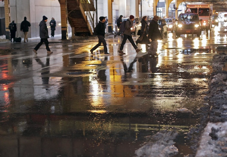 Image: Evening commuters navigate melting snow and puddles Tuesday as they head home in Chicago.