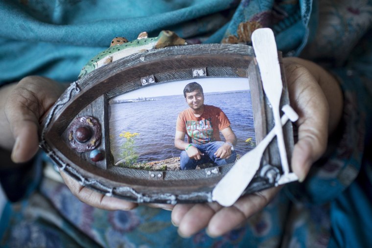 Image: Tanzeela Bajwa holds a photo of her son, Muhammad, who lies comatose in a hospital bed.
