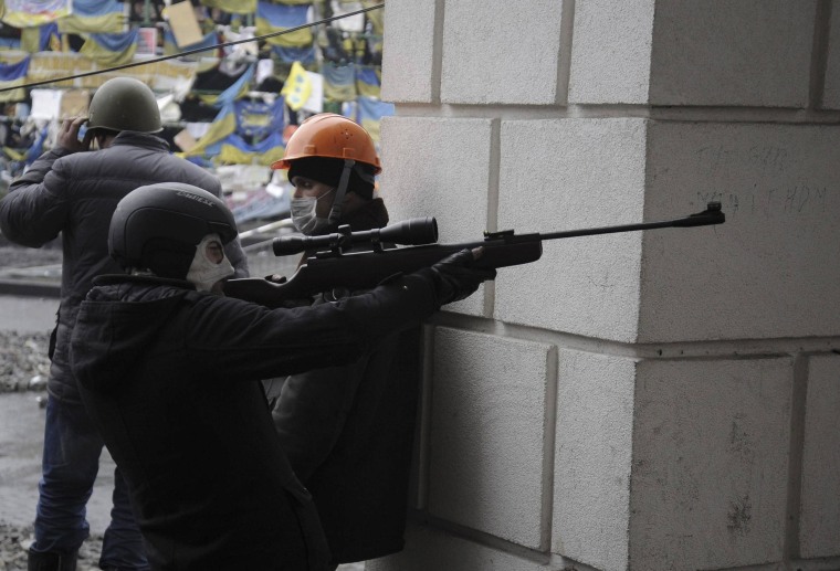 Image: An anti-government protester aims a rifle during clashes with riot police in Independence Square in Kiev
