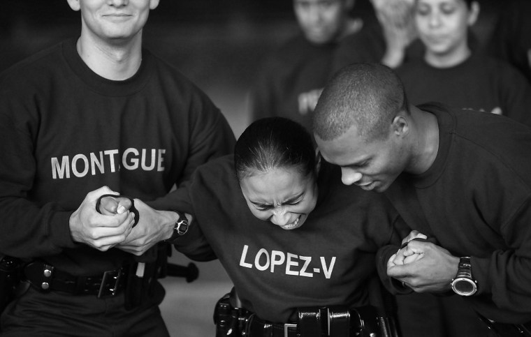 Image: Los Angeles Police recruits Chris Montague, left, and Clay Bell, right, hold Vanessa Lopez as her body is charged with taser voltage