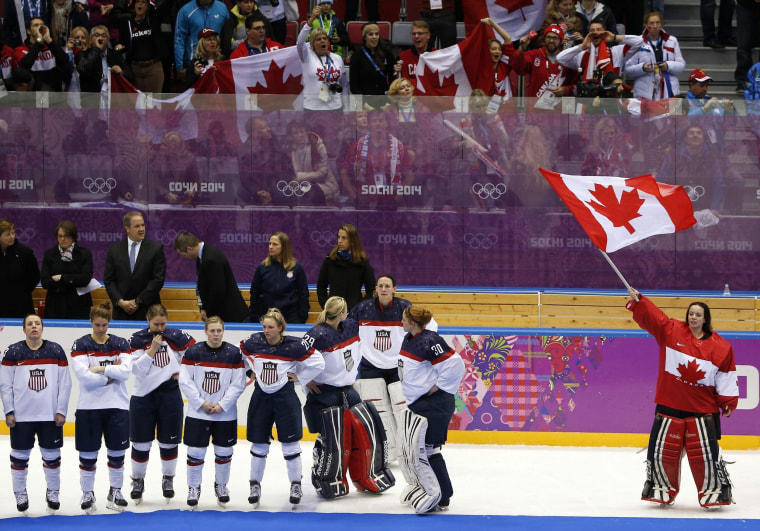 Canada's goalie Shannon Szabados (R) stands with her national flag near Team USA after Canada won their women's gold medal ice hockey game at the Sochi 2014 Winter Olympic Games February 20, 2014.   