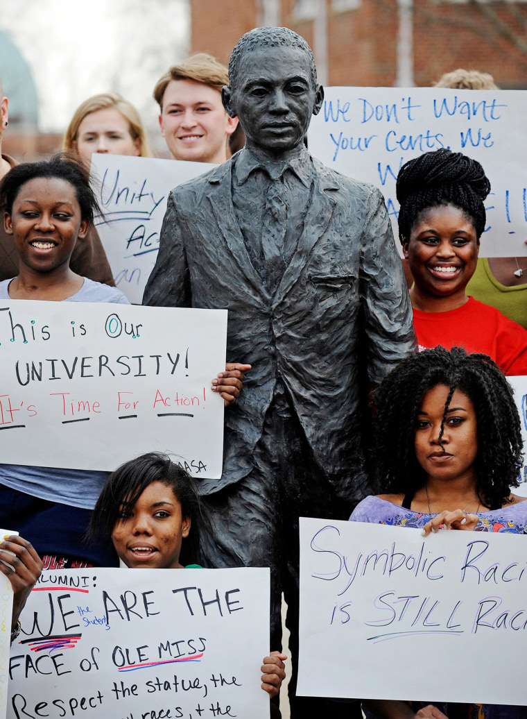 Image: Students hold signs while posing for a photo during a gathering in front of the James Meredith statue at the University of Mississippi