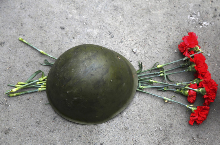 Image: Roses are placed under a combat helmet during a funeral service for two anti-governent protesters who were killed after days of violence in Kiev