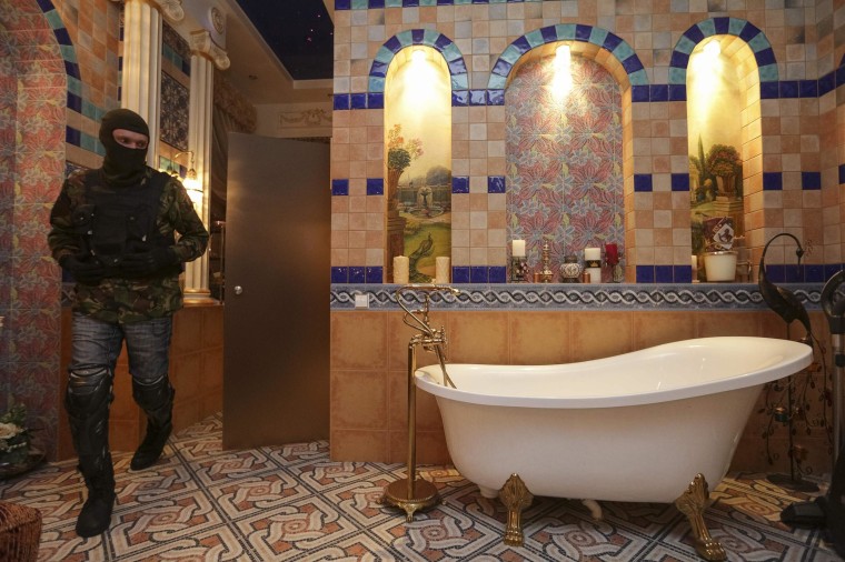 Image: A man walks past a bath tub in the house of Ukraine's former prosecutor general Pshonka in the village of Gorenichy outside Kiev