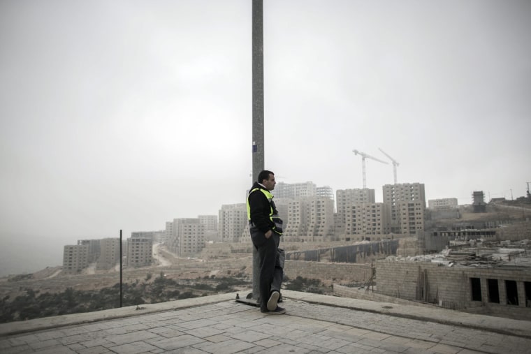 A Palestinian worker leans on a light pole after his shift in Rawabi, West Bank.