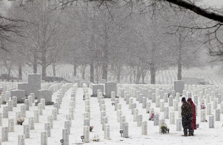 Image: Luis and Chip Drury pause at the grave of their son