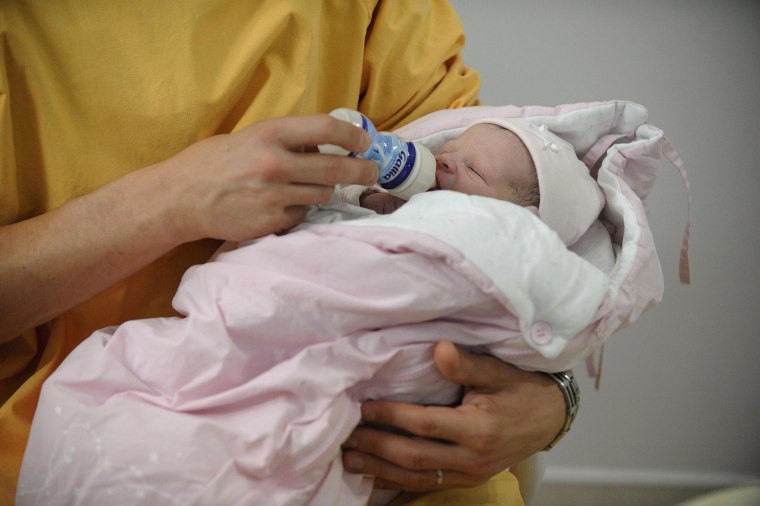 Image: A man gives the feeding bottle to his newborn baby at the maternity of the Angers hospital in Angers, western France