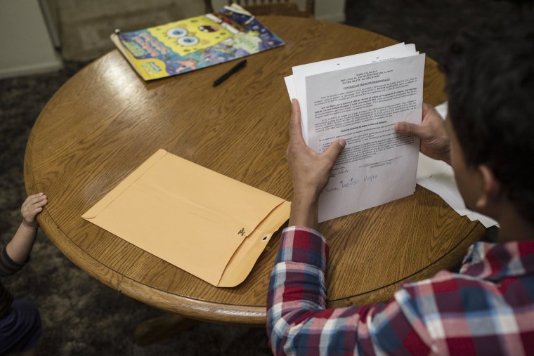 Image: Erlin Gomez flips through paperwork from his case