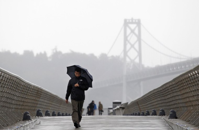 Image: A man walks down Pier 14 during a rain storm in San Francisco