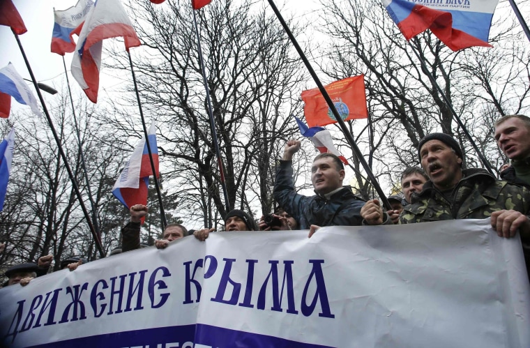 Image: People hold flags during a pro-Russian rally outside the Crimean parliament building in Simferopol