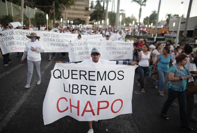 Image: A protester holds a sign reading, "We want Chapo free" during a march in Culiacan
