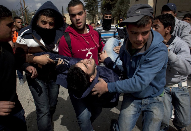 Image: An injured Palestinian man is evacuated toward an ambulance