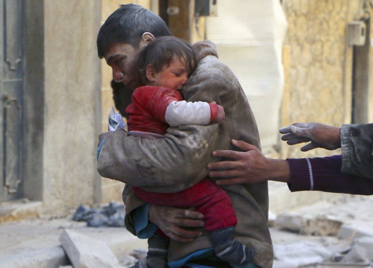 Image: A boy holds his baby sister saved from under rubble, who survived what activists say was an airstrike by forces loyal to Syrian President Bashar al-Assad in Masaken Hanano in Aleppo