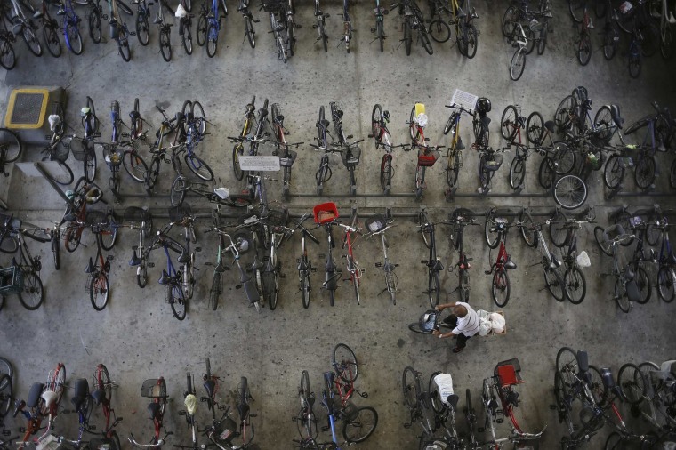 Image: A man rides off with his bicycle outside a train station in Singapore