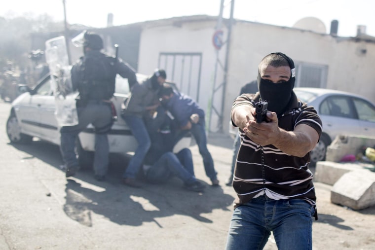 Image: Image: An Israeli undercover policeman point his gun (R) while other officers arrest a Palestinian stone thrower during clashes following Friday prayers at the east Jerusalem neighbourhood of Ras Al Amude