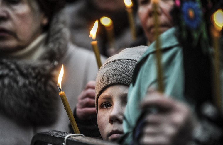 A boy looks on during the funeral of a man who was killed during last month's clashes with riot police on Kiev's Independence square on March 1, 2014. Pro-Russian forces tightened their grip on Crimea on March 1, 2014 as the Kremlin vowed to help restore calm on the restive Ukrainian peninsula and Washington warned of "costs" to Moscow should it order in troops.  