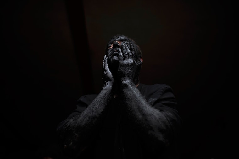 A man covers his face in oil and soot as he gets ready to participate in a carnival festival in the small village of Luzon, Spain.