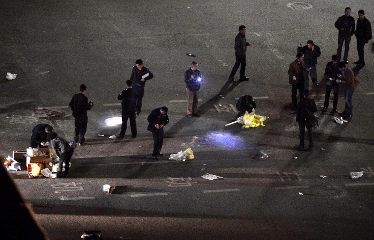 Image: TPolicemen investigate the scene outside the train station after a deadly attack by a group of knife-wielding men in Kunming