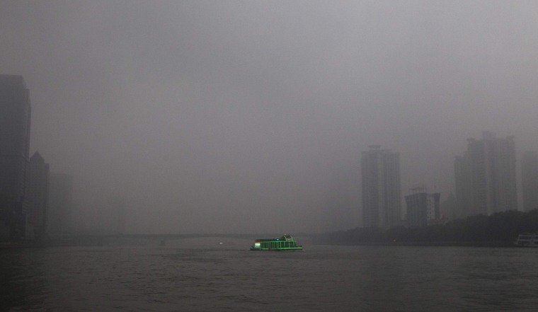 Image: A tourist boat, decorated with green lights, travels on the Pearl River amid heavy haze in Guangzhou.