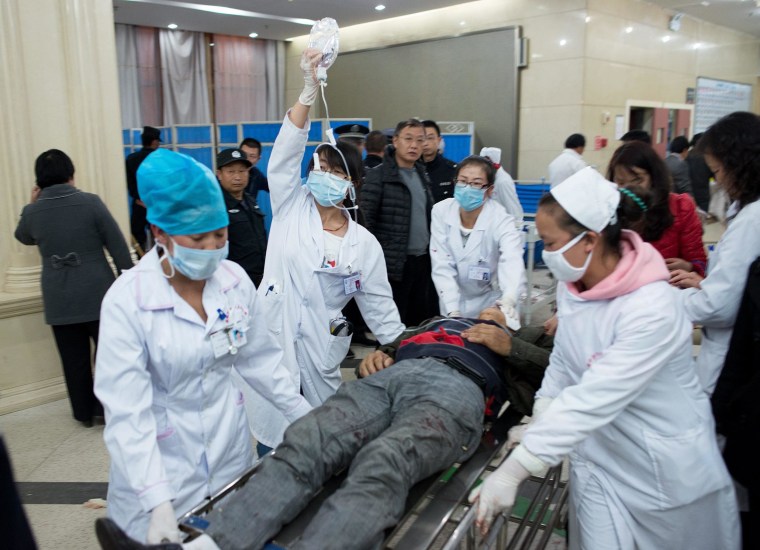 Image: Medical workers moving a man wounded in a deadly stabbing attack at a railway station in China