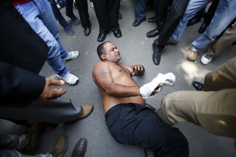 Image: An unidentified man, who threw ink on the face of the Sahara group chairman Subrata Roy, lies in the road after he was beaten by Roy's supporters at the Supreme Court premises in New Delhi