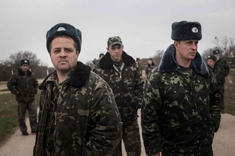 Image: Unarmed Ukrainian troops stare at Russian soldiers blocking Belbek airfield in Crimea.