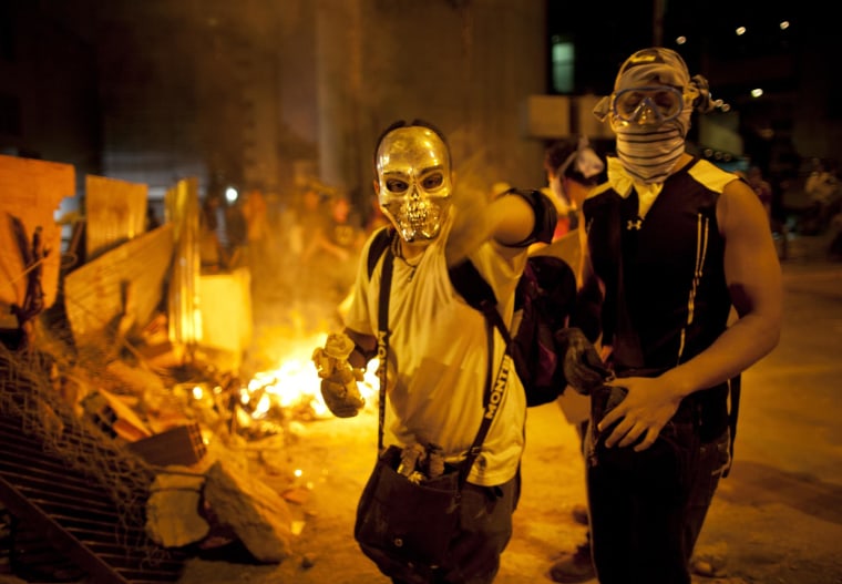 Image: A masked demonstrator prepares a Molotov cocktail during clashes in Caracas
