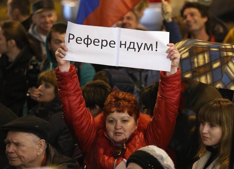 Image: Pro-Russian sympathizers, including one woman holding a sign that says "Referendum"